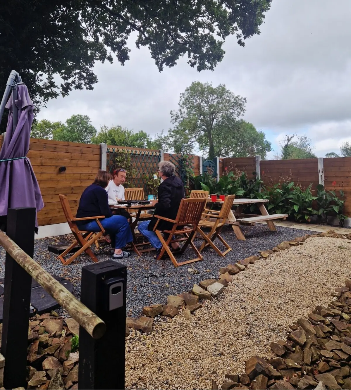 Des amis jouent au Scrabble autour de la table extérieure dans le jardin privé clos d'Ursula Gîte, près de Coutances, dans la Manche, en Normandie